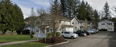 A parking lot with cars and a sign in front of a building.