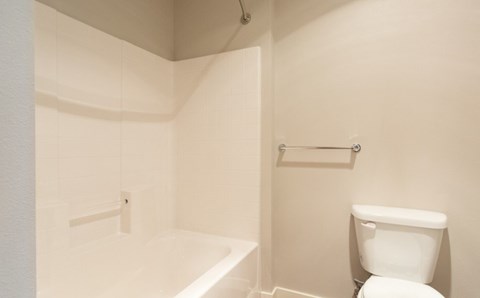 A white toilet sits next to a white bathtub in a small bathroom.