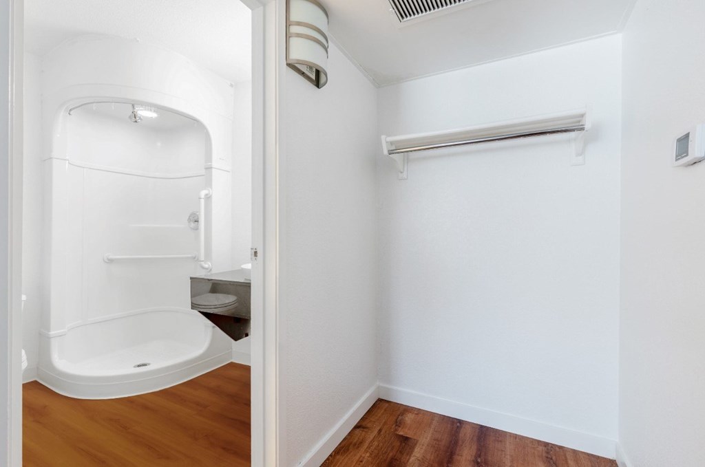 A white bathroom with a walk in shower and a towel bar.