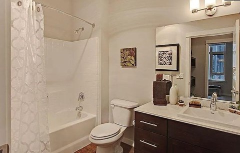 A white toilet sits in a bathroom next to a sink and a shower.