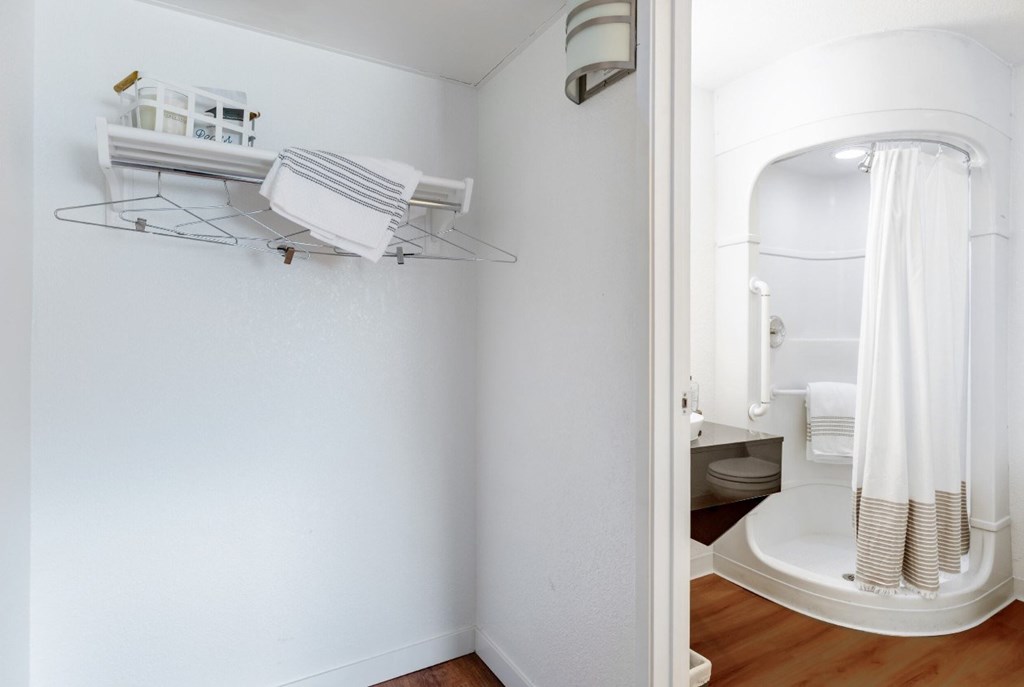 A white bathroom with a towel rack and a shower.