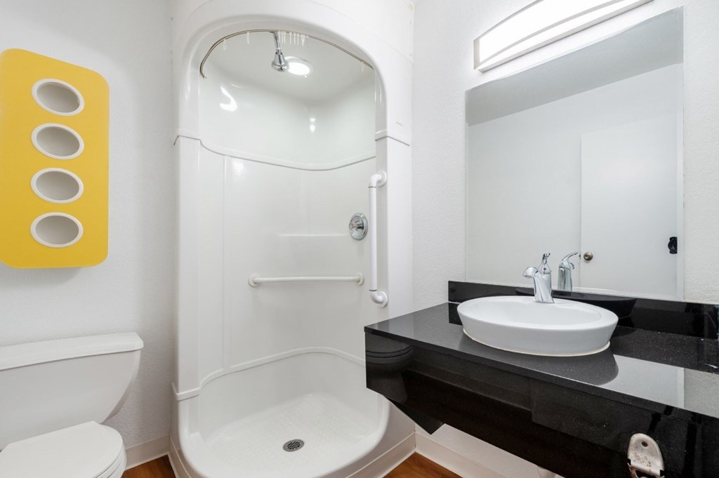 A bathroom with a white toilet, a white sink, and a white shower.