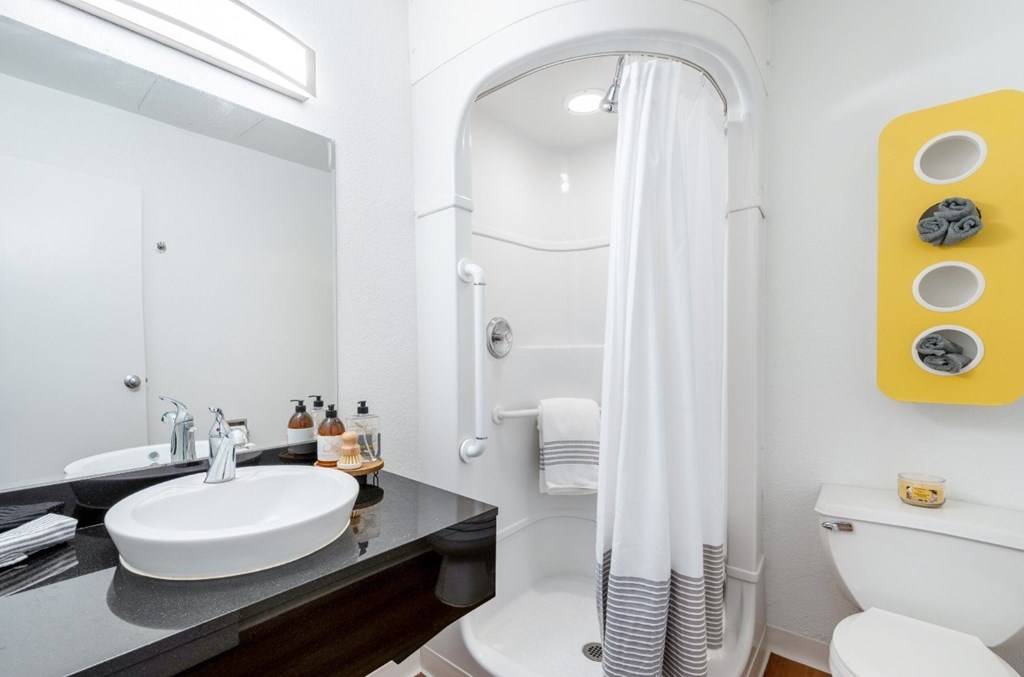 A bathroom with a white toilet, sink, and shower.