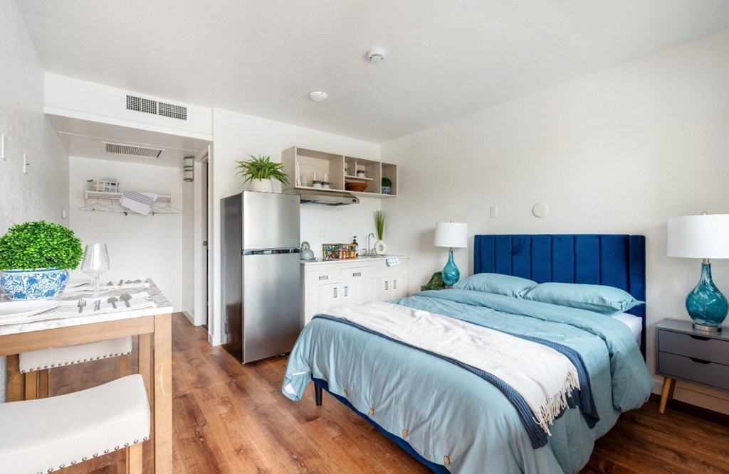 A bedroom with a bed, nightstand, and a dining table with chairs.