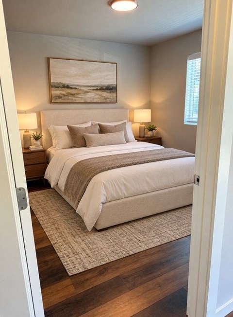 A bedroom with a large bed and a painting on the wall.