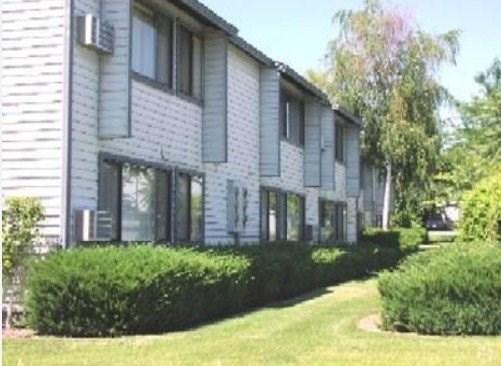 A white building with a green lawn in front.