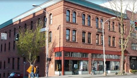 A red brick building with a green roof and a sign that says "The Standard".
