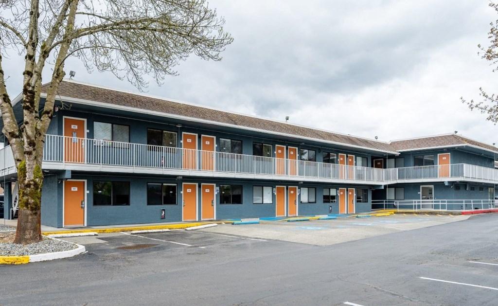 A parking lot in front of a building with orange doors.