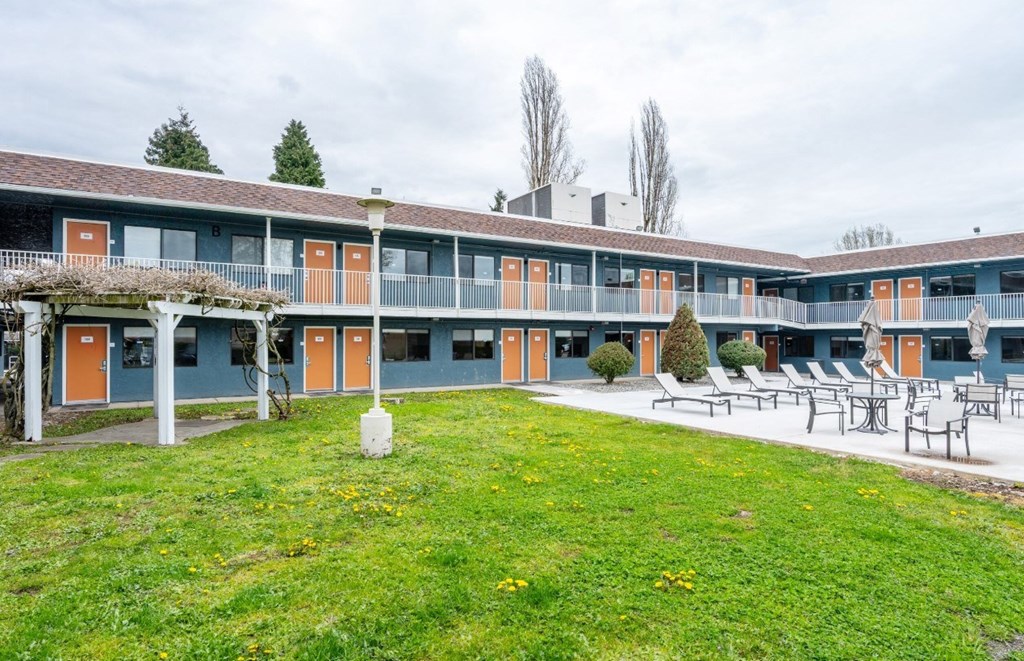 A building with orange doors and a green lawn in front.
