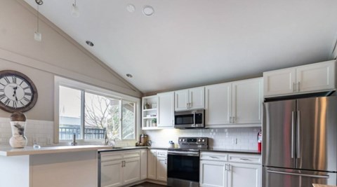 A kitchen with white cabinets and a stainless steel refrigerator.