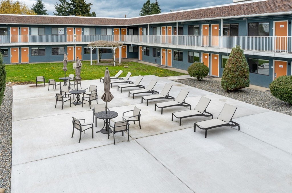 A patio with chairs and a table in front of a building.