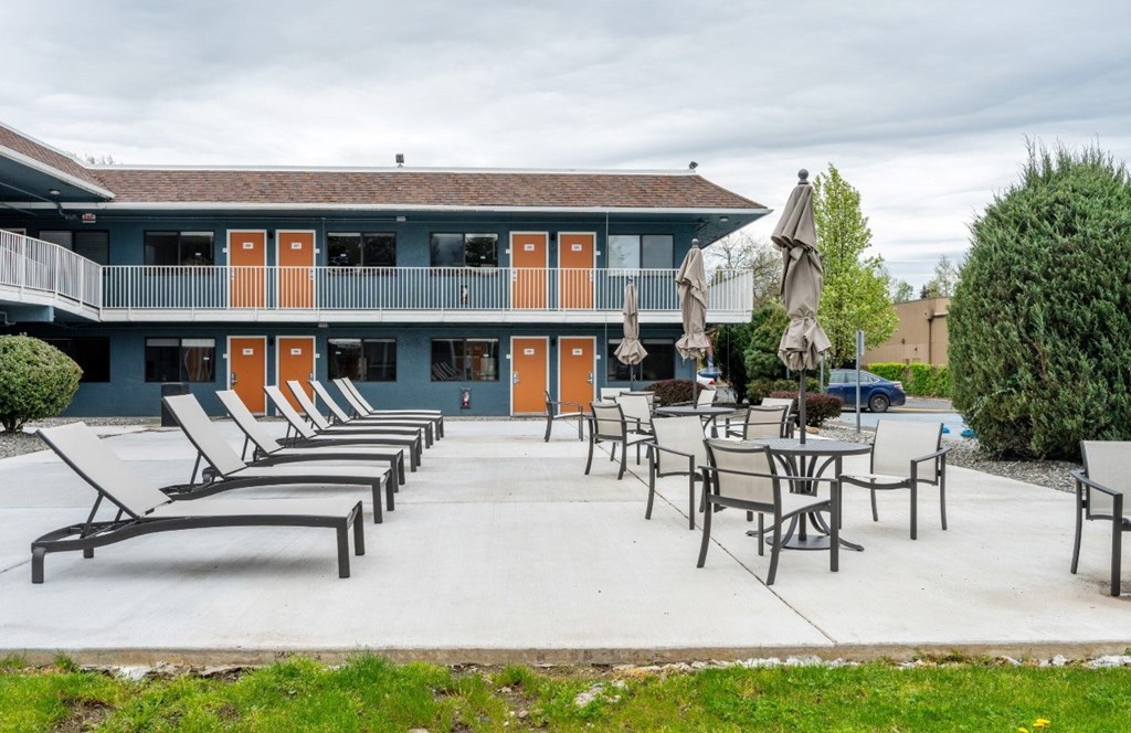 A patio area with chairs and tables is in front of a building with orange doors.