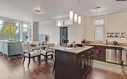 A kitchen with a wooden floor and a black fridge.