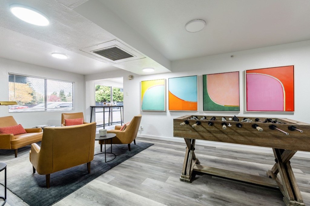 A room with a foosball table and chairs.