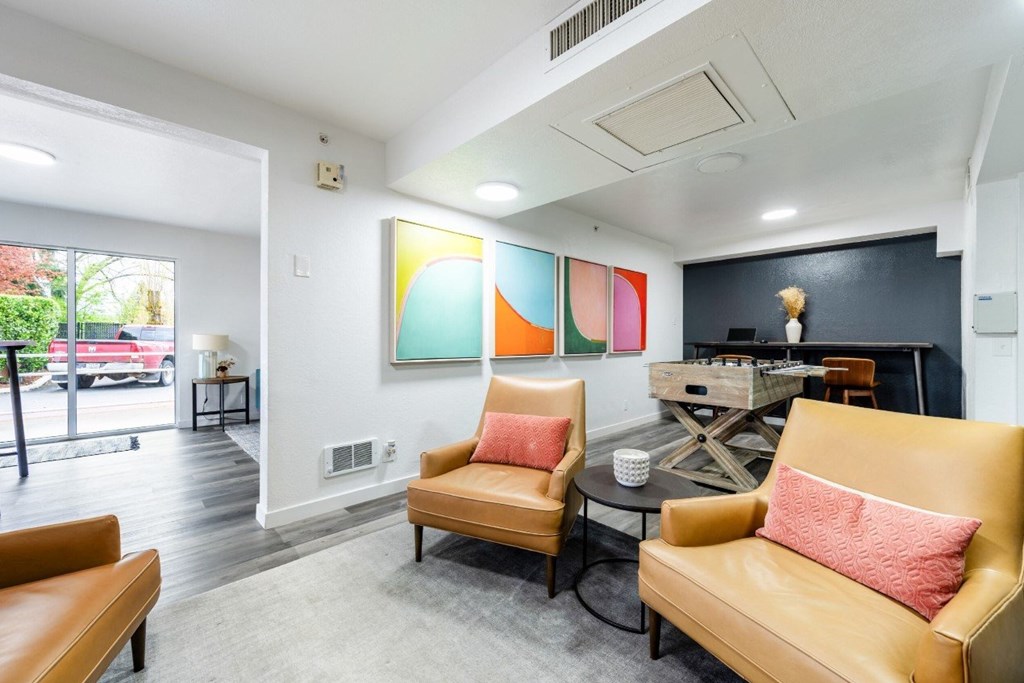 A living room with a yellow couch and a painting on the wall.