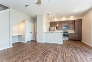 an empty living room and kitchen with wood flooring