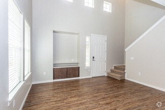 an empty living room with wood flooring and a door to a bathroom