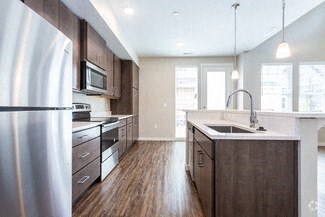 a large kitchen with wooden floors and stainless steel appliances