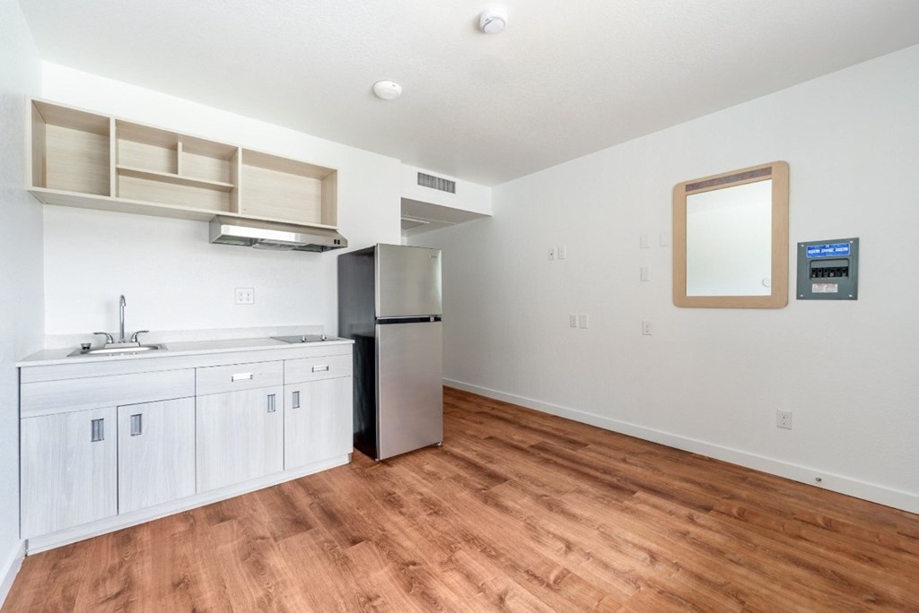 A kitchen with white cabinets and a wooden floor.