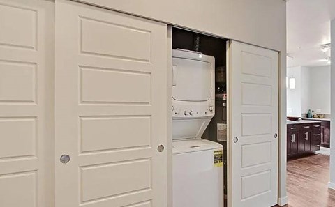 A white door is open to a room with a washing machine in it.