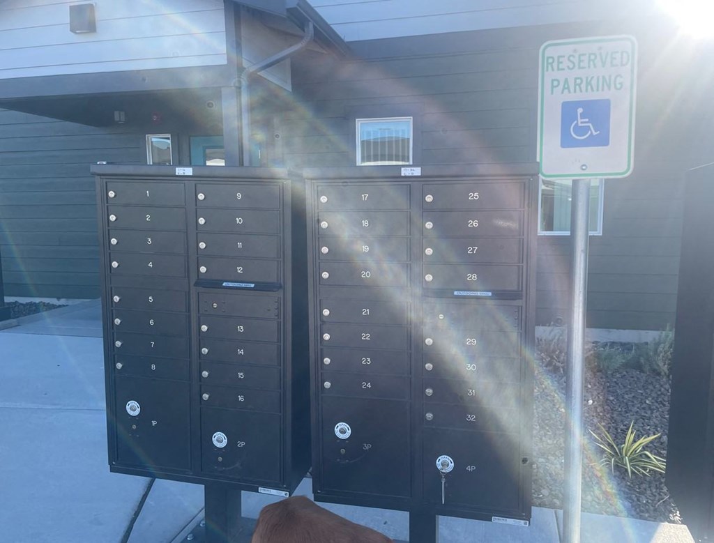 a row of mailboxes in front of a building with a reserved parking sign