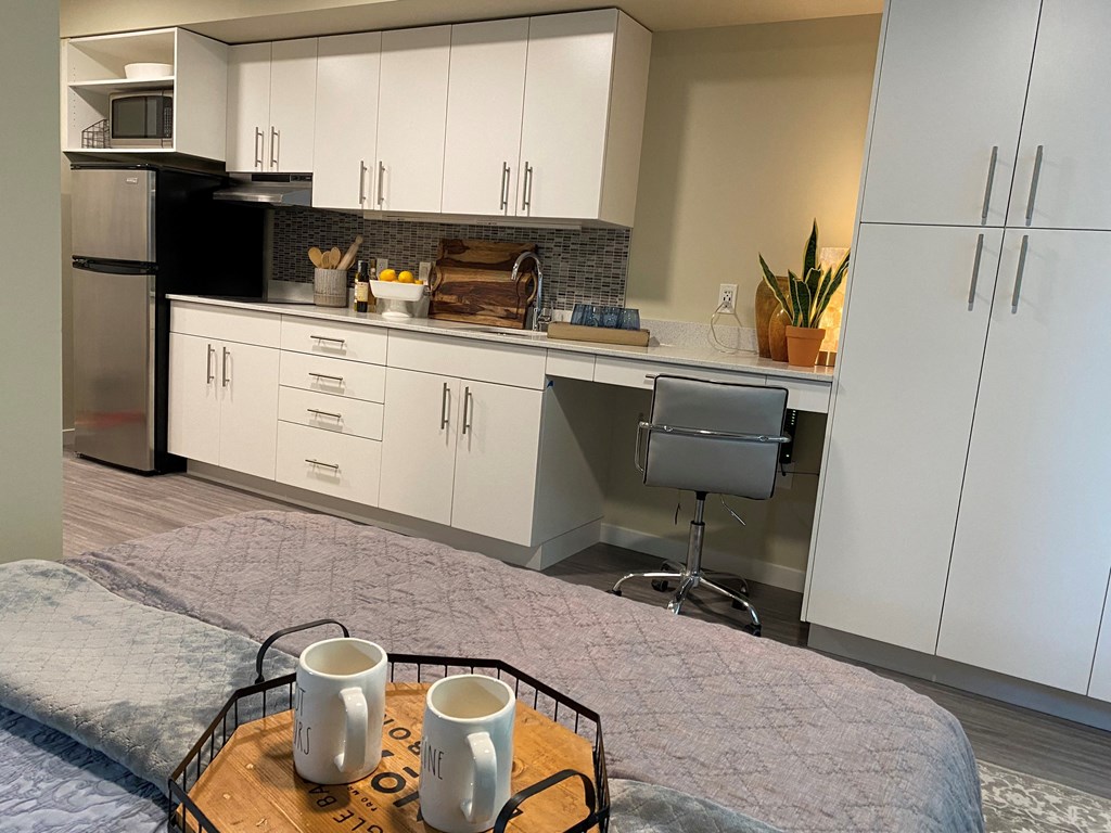a kitchen with white cabinets and a table with coffee mugs on it
