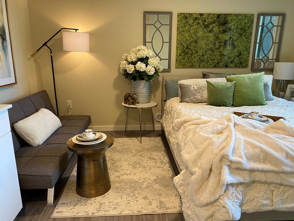 a bedroom with a couch and a bed and a painting on the wall