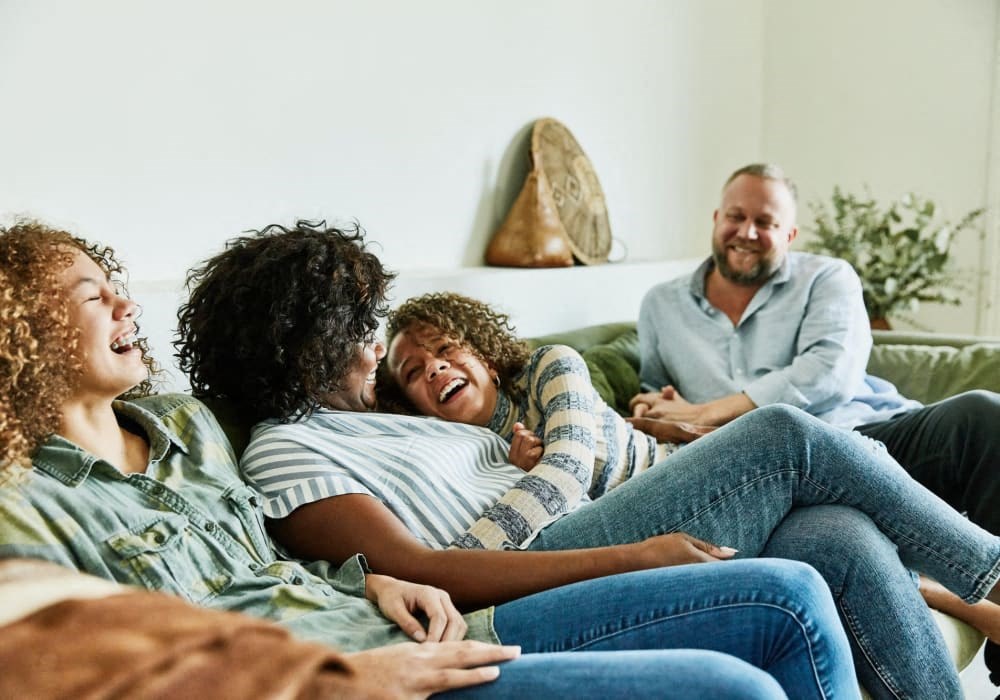 A group of people sitting on a couch, laughing and enjoying each other's company.