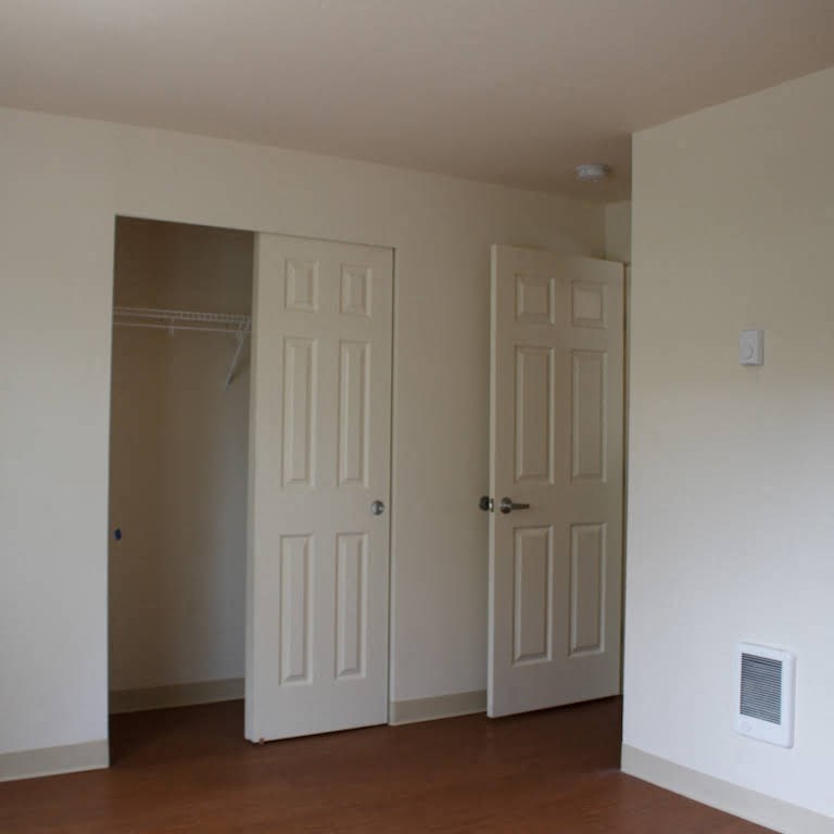 an empty room with two doors and a closet