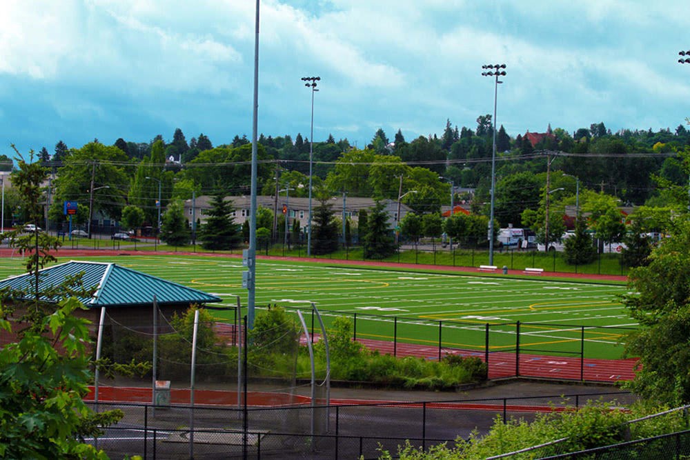 A view of a track field with a green roofed structure on the left.