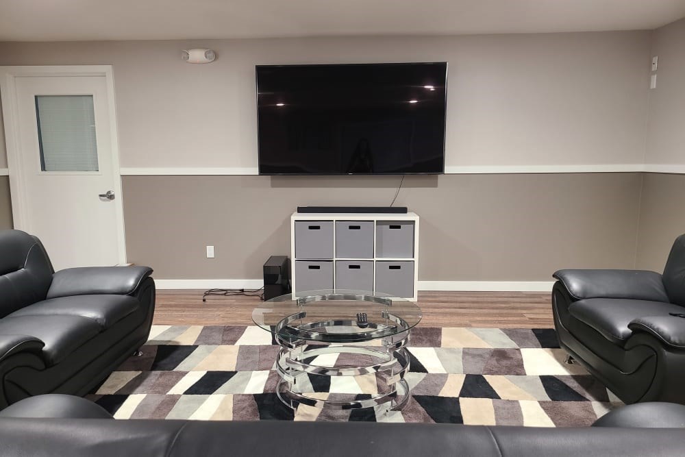 A black leather couch sits in front of a television in a living room.