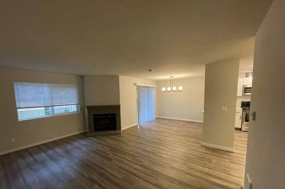 A spacious living room with a fireplace and hardwood floors.