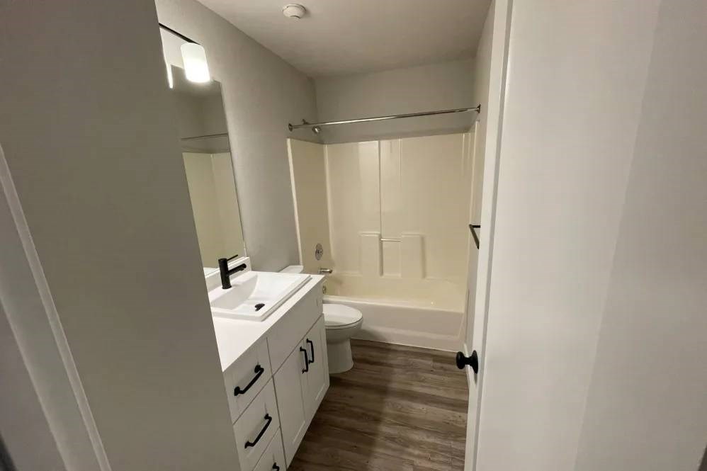 A white bathroom with a sink, mirror, and toilet.