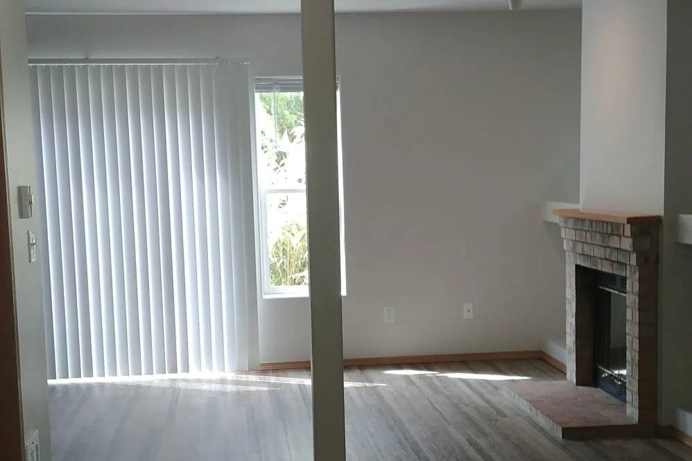 A room with a fireplace and a window with blinds.