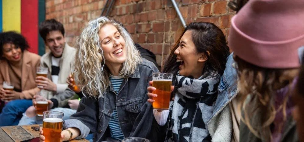 a group of people sitting around a table drinking beer