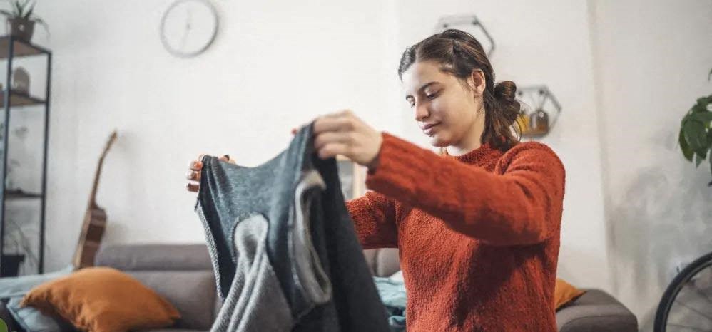 a woman is looking at a pile of clothes in her living room