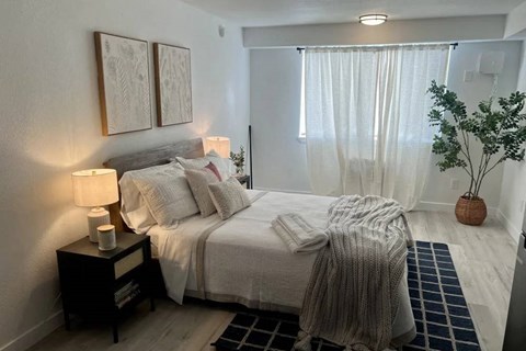 A bedroom with a bed, nightstand, and two framed pictures on the wall.