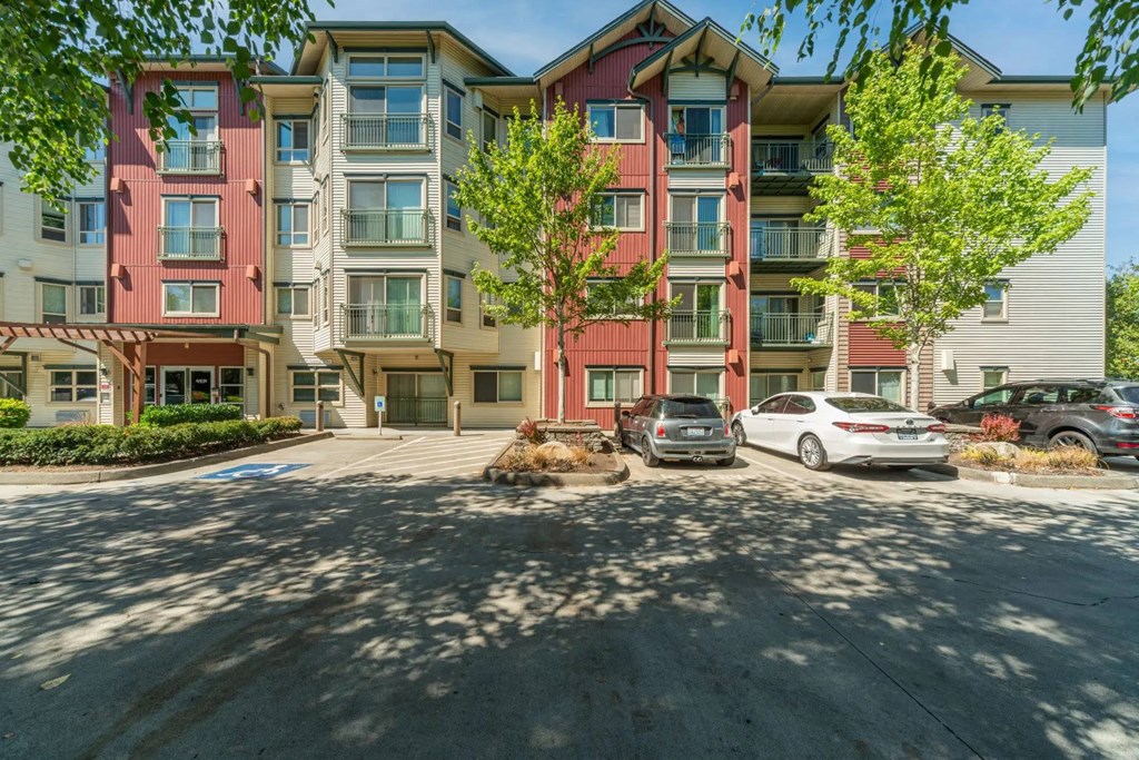 A red and beige apartment building with cars parked in front.