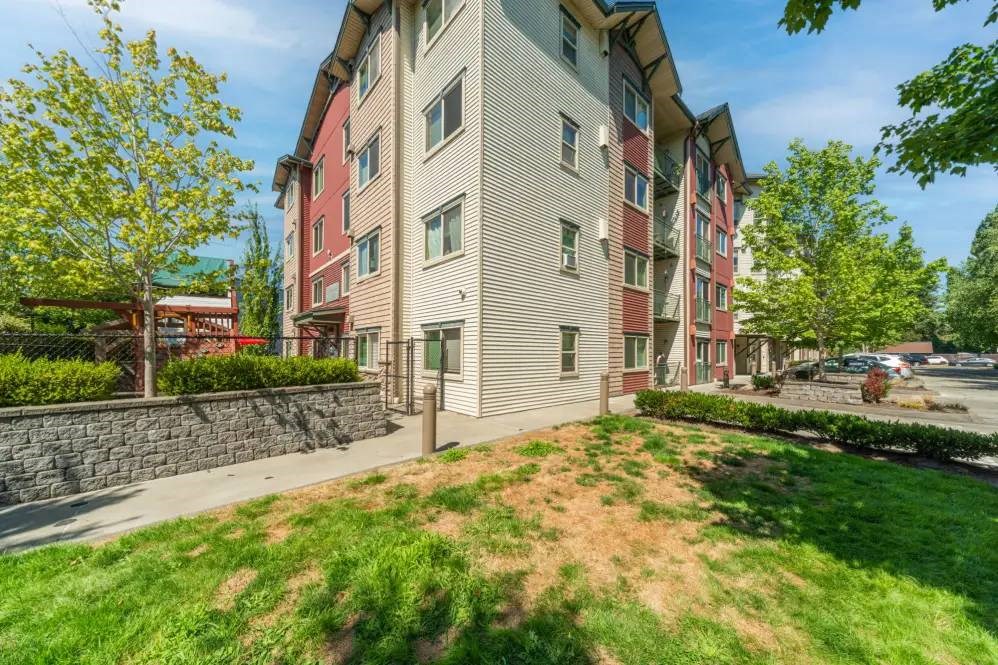 A multi-story apartment building with a red awning and a stone wall in front.