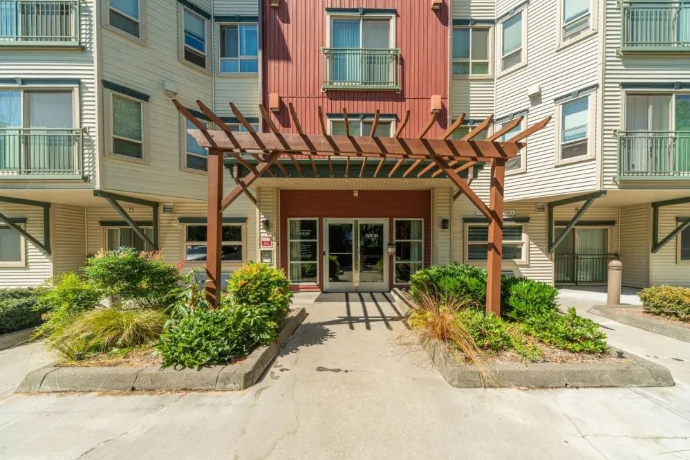 A building with a red and white facade has a wooden pergola in front.