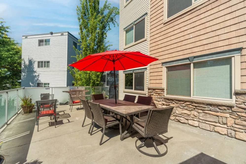 A patio with a table and chairs under a red umbrella.
