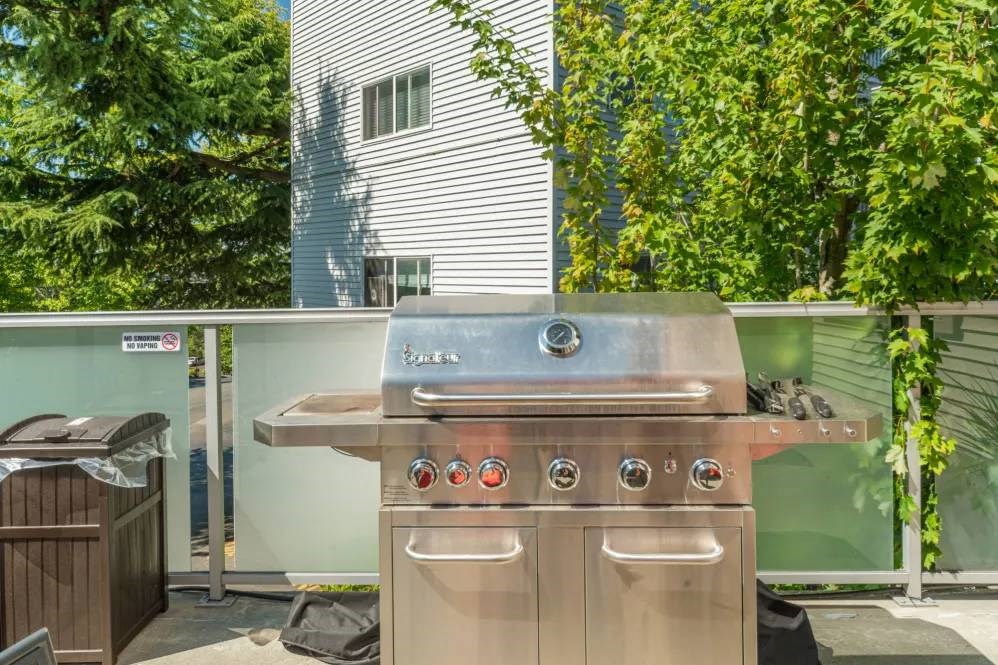 A stainless steel outdoor grill with four burners is on a balcony.