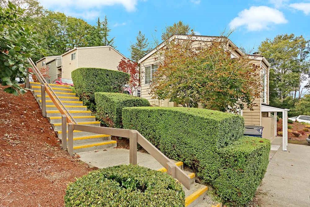 A house with a yellow staircase and green bushes.