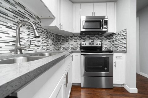 A modern kitchen with a stainless steel oven and a stone backsplash.