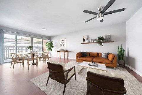 A living room with a brown couch, a brown chair, and a white ceiling fan.
