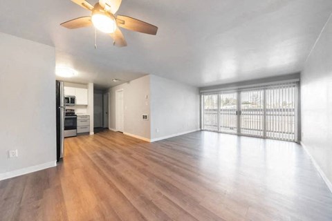 A room with a ceiling fan and sliding glass doors.