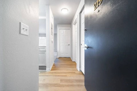 A hallway with a white door and a black wall with a gold number 23 on it.