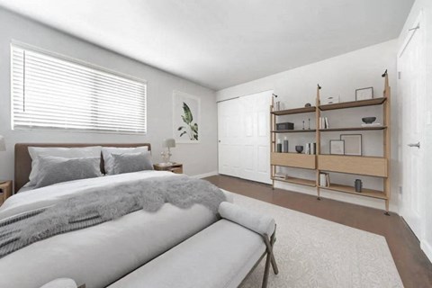 A bedroom with a bed, a bench, and a shelf with items on it.