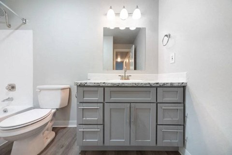 A bathroom with a toilet, sink, and a mirror.