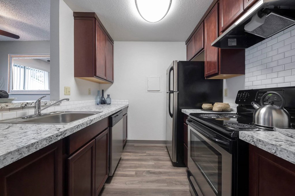 A kitchen with brown cabinets and a black refrigerator.